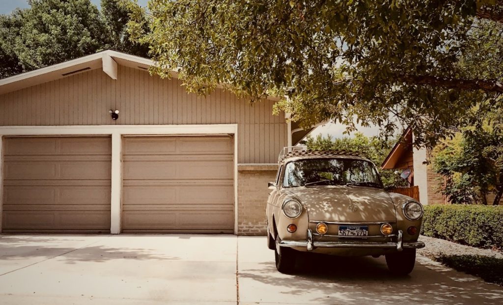 An old car parked in the driveway of an American house